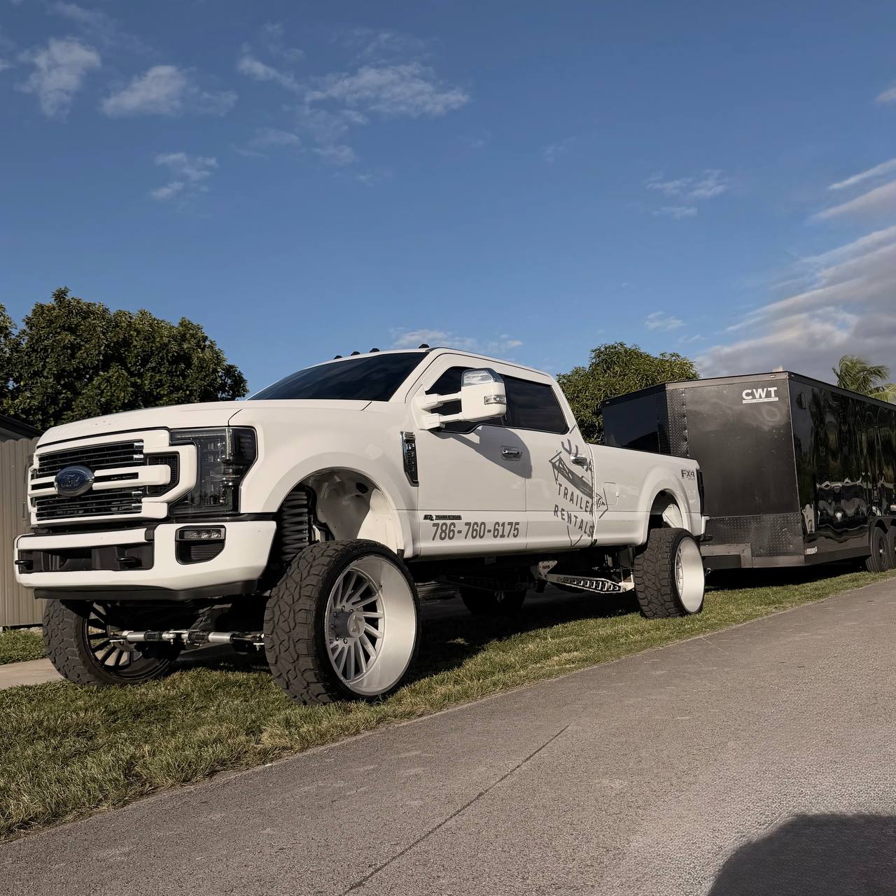 Pickup truck towing a car on a trailer at sunset